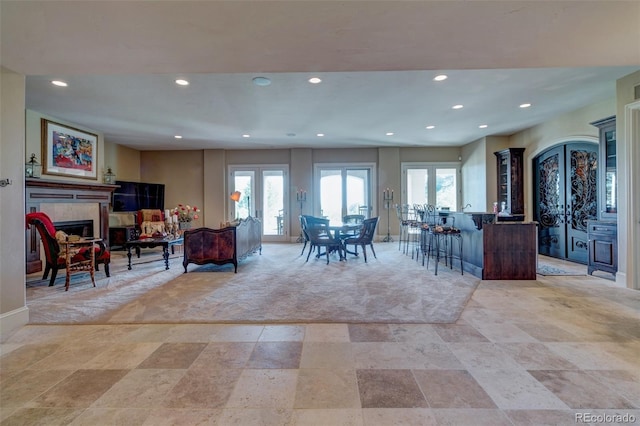 interior space featuring light colored carpet, french doors, and a tiled fireplace