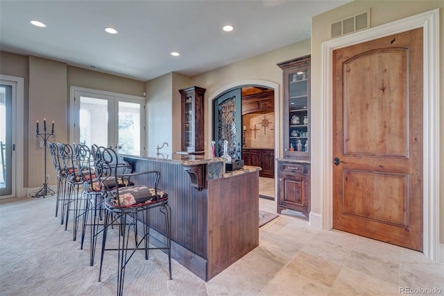 kitchen with a breakfast bar, light carpet, french doors, and a kitchen island