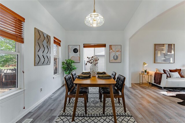 2875 S Tower Way, Aurora, CO 80013 - dining space featuring a chandelier, light wood-style floors, and arched walkways