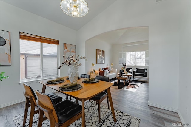 2875 S Tower Way, Aurora, CO 80013 - dining area featuring lofted ceiling, a chandelier, arched walkways, and wood finished floors