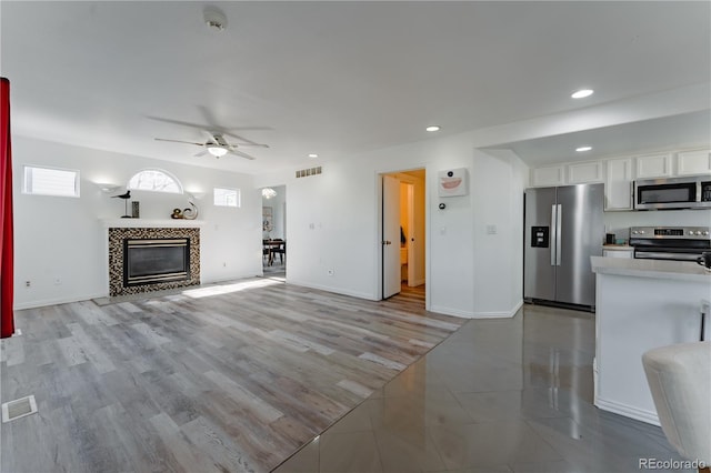 2875 S Tower Way, Aurora, CO 80013 - unfurnished living room featuring ceiling fan, recessed lighting, a tiled fireplace, and light wood-style flooring