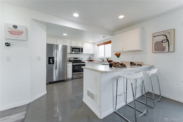 2875 S Tower Way, Aurora, CO 80013 - kitchen with stainless steel appliances, a peninsula, white cabinets, recessed lighting, and light countertops