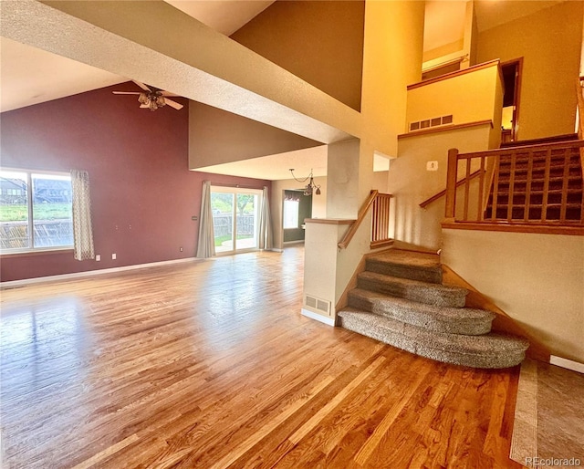 10064 Westside Cir, Littleton, CO 80125 - stairs with wood finished floors, high vaulted ceiling, a ceiling fan, and a chandelier