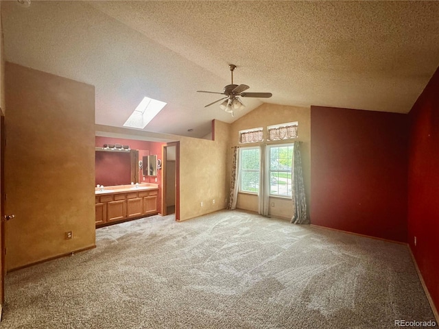 10064 Westside Cir, Littleton, CO 80125 - empty room featuring a skylight, a ceiling fan, lofted ceiling, light carpet, and a textured ceiling