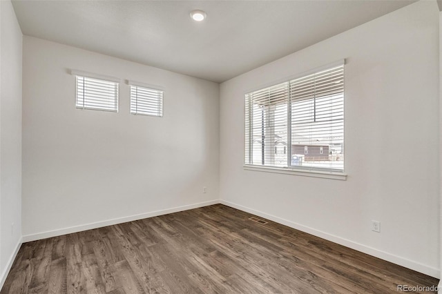 empty room featuring plenty of natural light and dark hardwood / wood-style floors