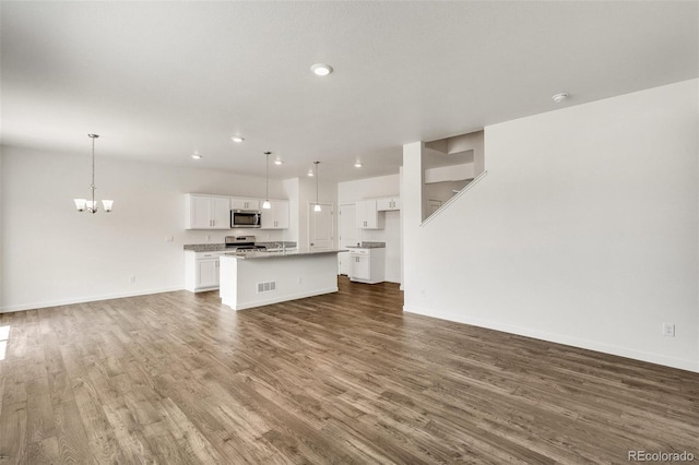 unfurnished living room featuring dark wood-type flooring and a chandelier