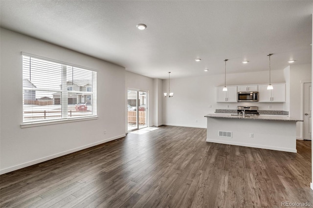 unfurnished living room with sink, dark wood-type flooring, and a notable chandelier