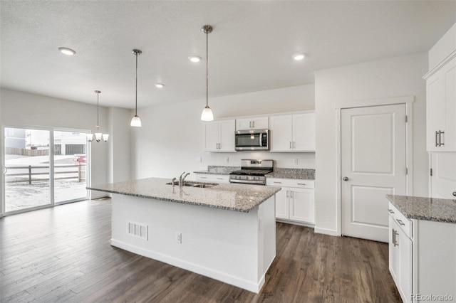 kitchen with a center island with sink, light stone countertops, white cabinets, and appliances with stainless steel finishes