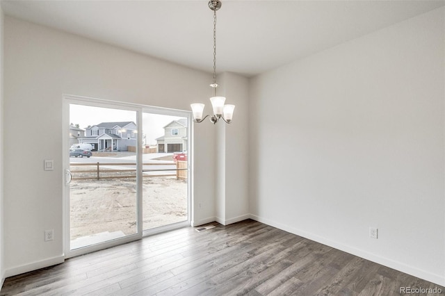 unfurnished dining area with wood-type flooring and a notable chandelier