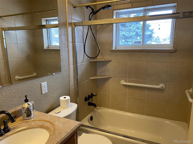 bathroom with toilet, a textured wall, vanity, and a wealth of natural light