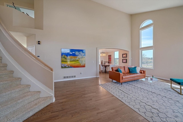 living room featuring visible vents, plenty of natural light, a towering ceiling, and stairway