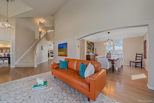 living area with stairway, wood finished floors, a chandelier, arched walkways, and baseboards