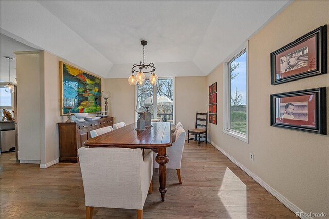 dining space with baseboards, an inviting chandelier, and light wood-type flooring
