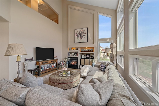 living room with a glass covered fireplace and a high ceiling