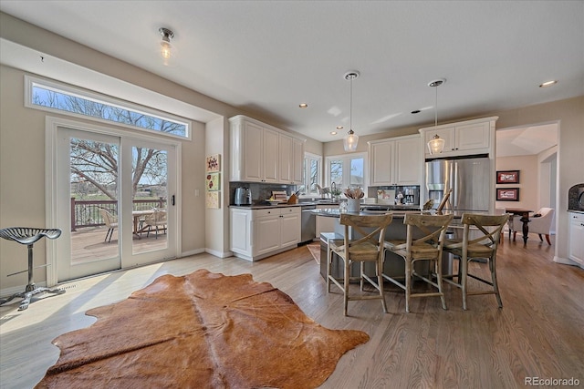 kitchen featuring white cabinets, stainless steel appliances, a center island, dark countertops, and decorative backsplash
