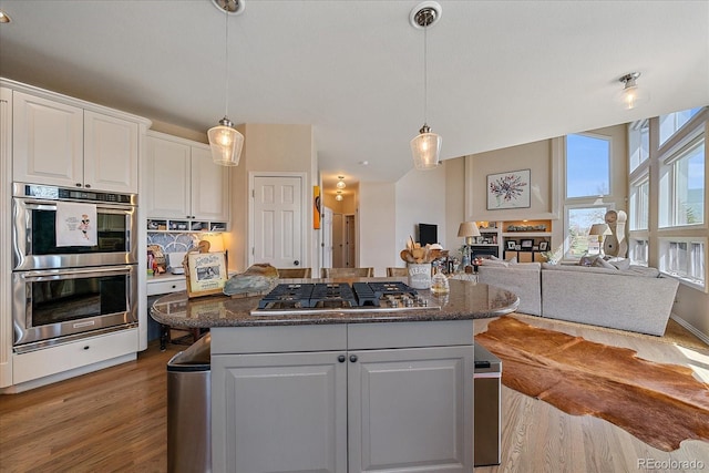 kitchen with light wood finished floors, a kitchen island, appliances with stainless steel finishes, and white cabinetry