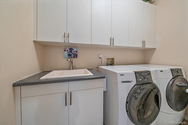 clothes washing area featuring washing machine and clothes dryer, cabinet space, and a sink