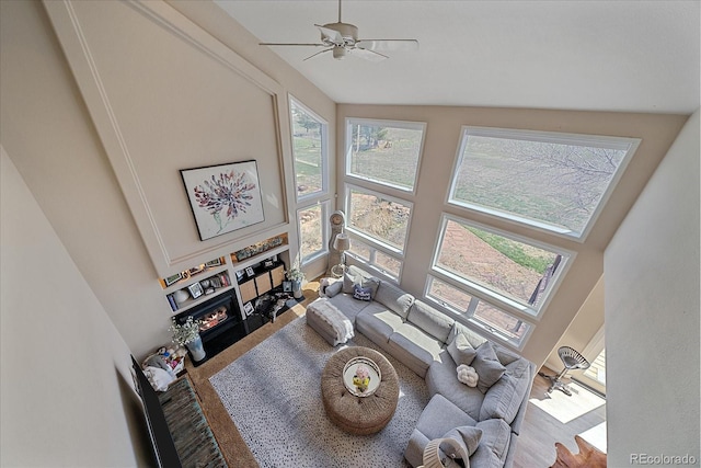 living area featuring a fireplace with flush hearth, a healthy amount of sunlight, and a towering ceiling
