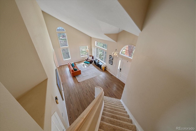 staircase featuring high vaulted ceiling, baseboards, and wood finished floors