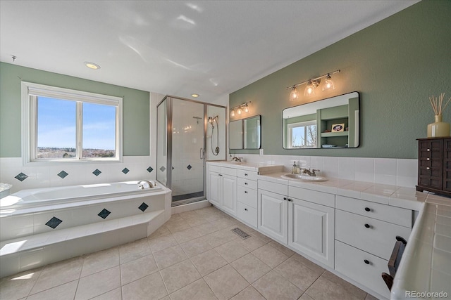 bathroom featuring double vanity, visible vents, a sink, a garden tub, and a stall shower