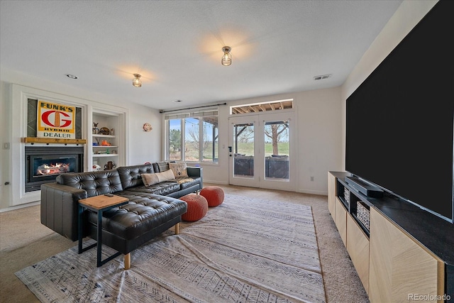 living area with light carpet, a glass covered fireplace, french doors, and baseboards