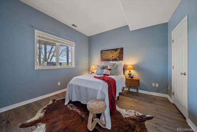 bedroom featuring wood finished floors, visible vents, and baseboards