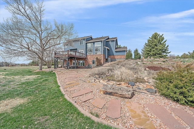 rear view of house featuring a lawn and a deck