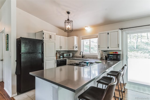 7256 Aspen Meadow Dr, Evergreen, CO 80439 - kitchen featuring black appliances, a peninsula, white cabinetry, and a kitchen bar