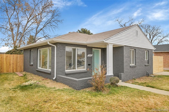 bungalow-style house with brick siding, a front yard, and fence