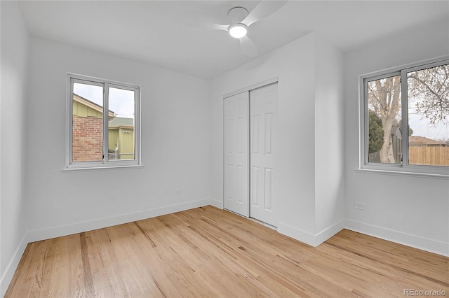 unfurnished bedroom featuring baseboards, multiple windows, and light wood finished floors