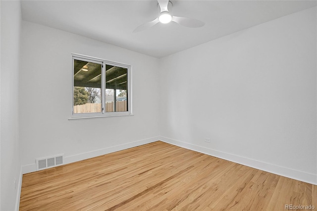 empty room with a ceiling fan, wood finished floors, visible vents, and baseboards