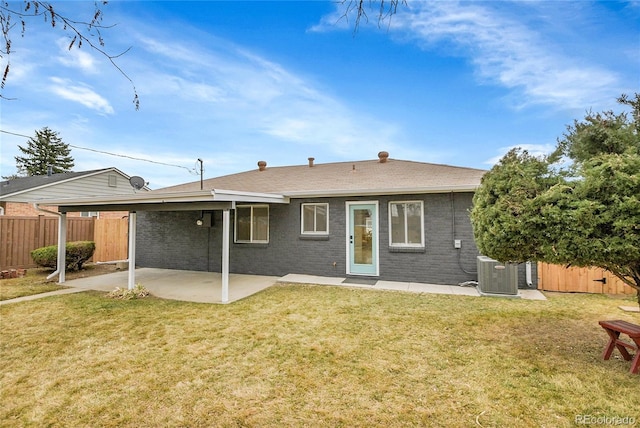 rear view of house with brick siding, fence, central AC, a yard, and a patio area