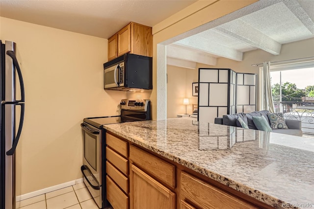 kitchen with a textured ceiling, beam ceiling, appliances with stainless steel finishes, light tile patterned floors, and light stone countertops