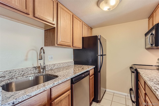 kitchen featuring light stone countertops, black appliances, light tile patterned floors, and sink