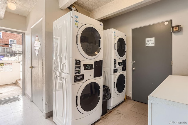 washroom with separate washer and dryer, a textured ceiling, and stacked washing maching and dryer