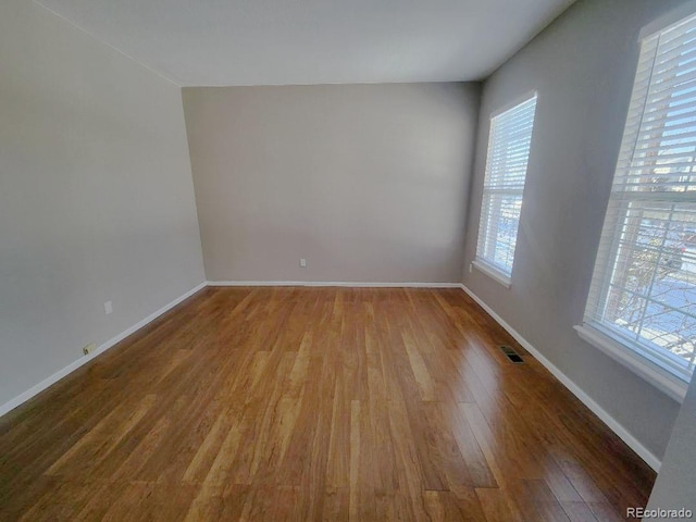 unfurnished room with hardwood / wood-style flooring and a healthy amount of sunlight