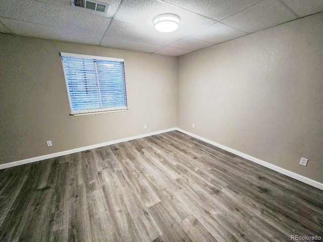 empty room featuring wood-type flooring and a paneled ceiling