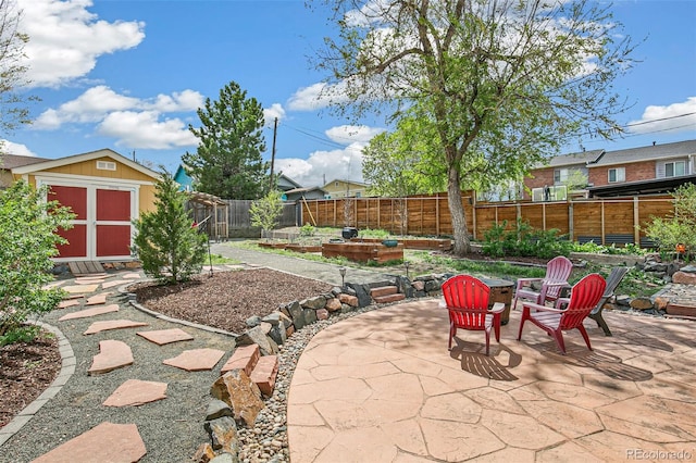 view of patio / terrace with a fenced backyard, a storage shed, a vegetable garden, and an outbuilding