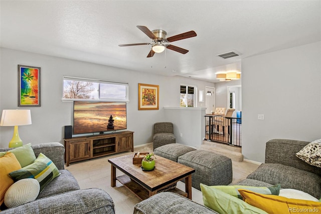 living room featuring a ceiling fan, baseboards, visible vents, and light colored carpet