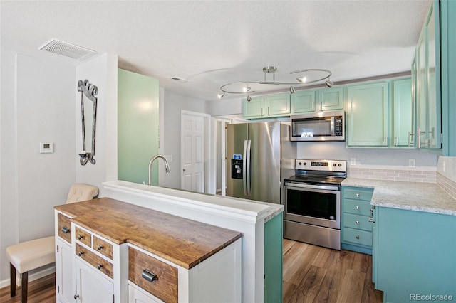 kitchen with light countertops, visible vents, appliances with stainless steel finishes, and dark wood-type flooring