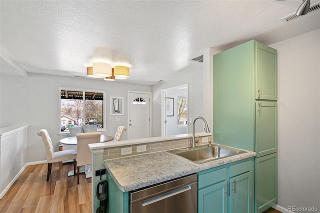 kitchen featuring stainless steel dishwasher, green cabinets, visible vents, a sink, and light wood-type flooring