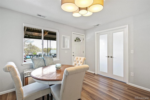 dining room with french doors, wood finished floors, visible vents, and baseboards