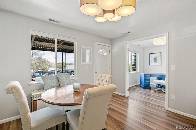 dining space with baseboards, visible vents, and wood finished floors