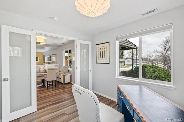 office area with light wood finished floors, baseboards, and visible vents