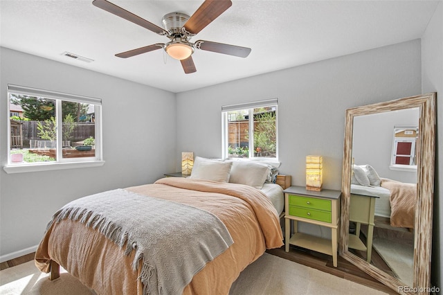 bedroom featuring baseboards, visible vents, a ceiling fan, and wood finished floors