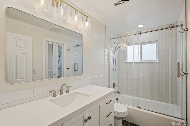 full bathroom with toilet, vanity, visible vents, and shower / bath combination with glass door