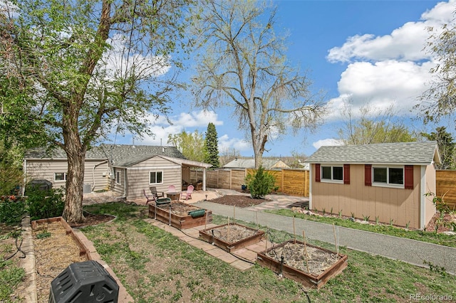 view of yard featuring a fenced backyard, a storage shed, a garden, and an outbuilding
