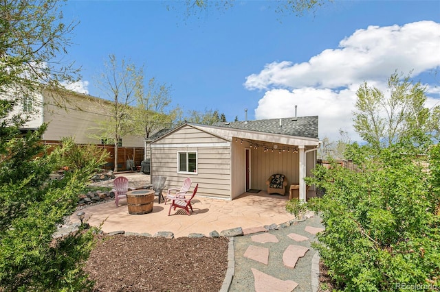 back of house featuring a patio area, roof with shingles, a fire pit, and fence