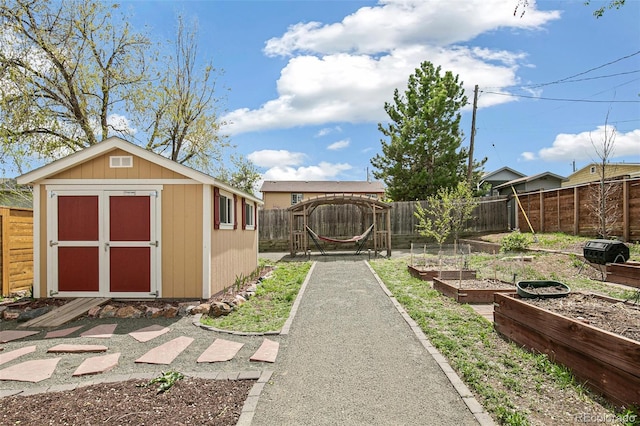 view of yard with a garden, an outbuilding, a fenced backyard, and a storage unit