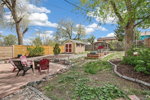 view of yard featuring a storage unit, a fenced backyard, a patio, and an outbuilding